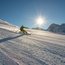Skifahrer fährt bei sonnigem Wetter auf schneebedeckter Piste in den Bergen
